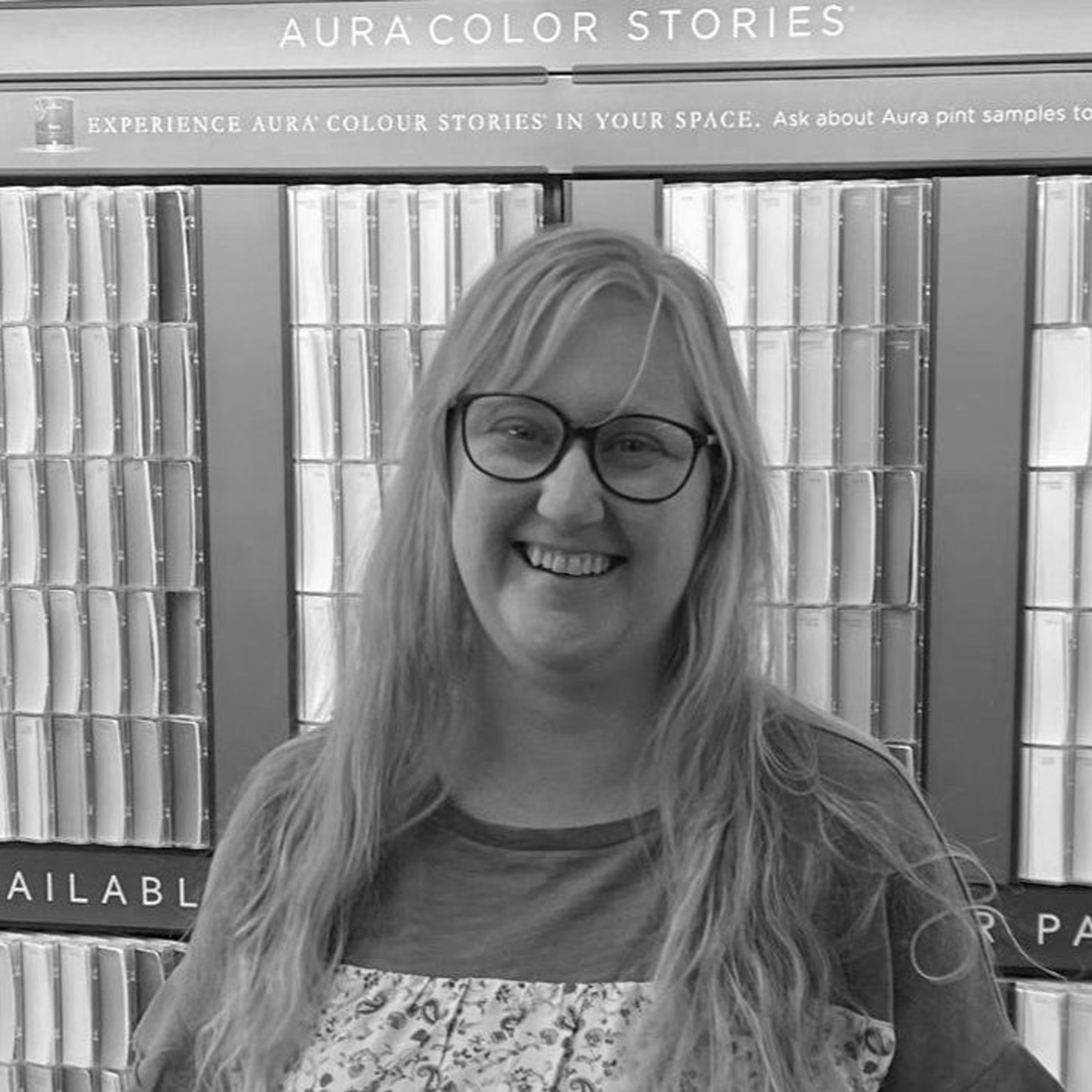 A woman wearing glasses is smiling in a black and white photo.