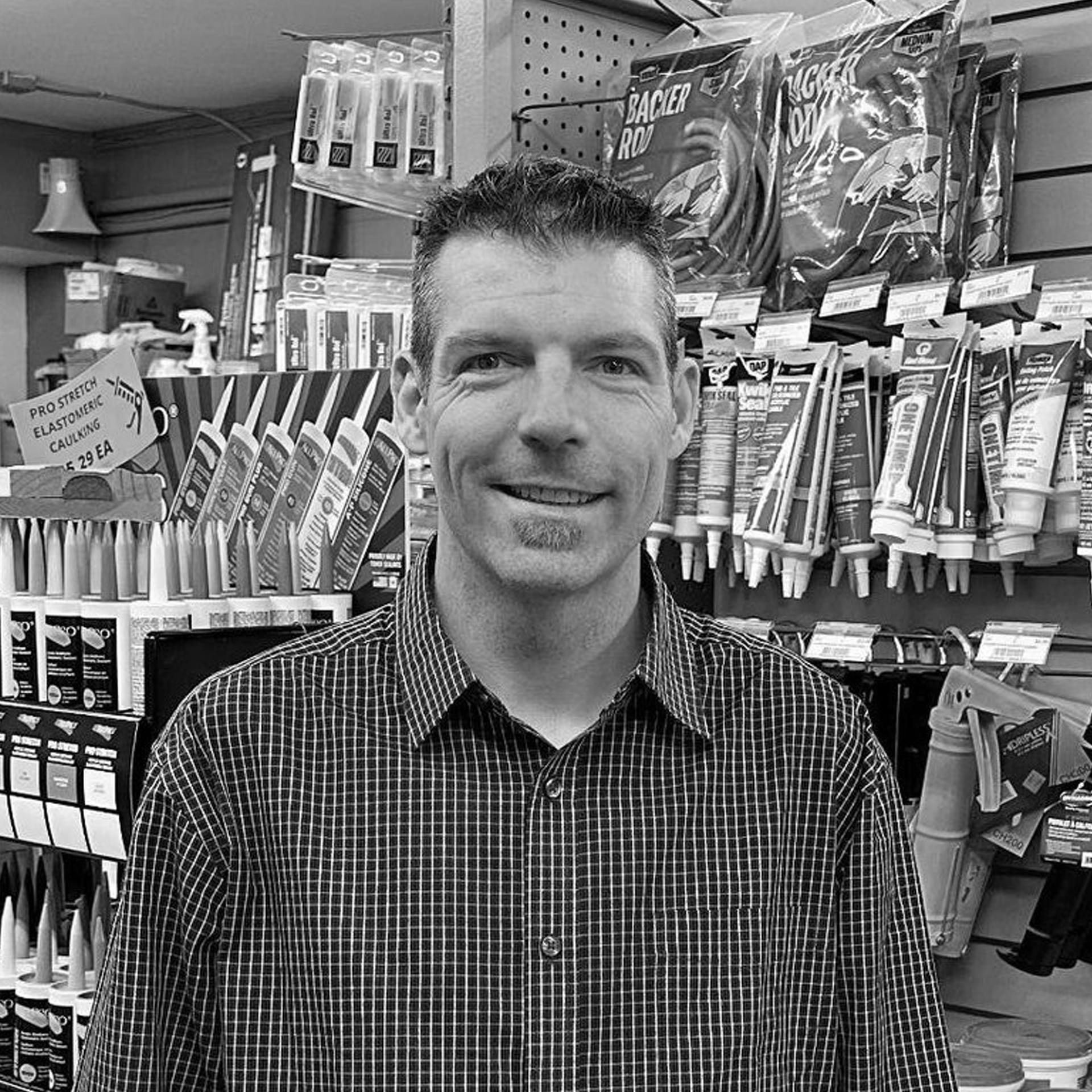 A man in a plaid shirt is standing in a store.