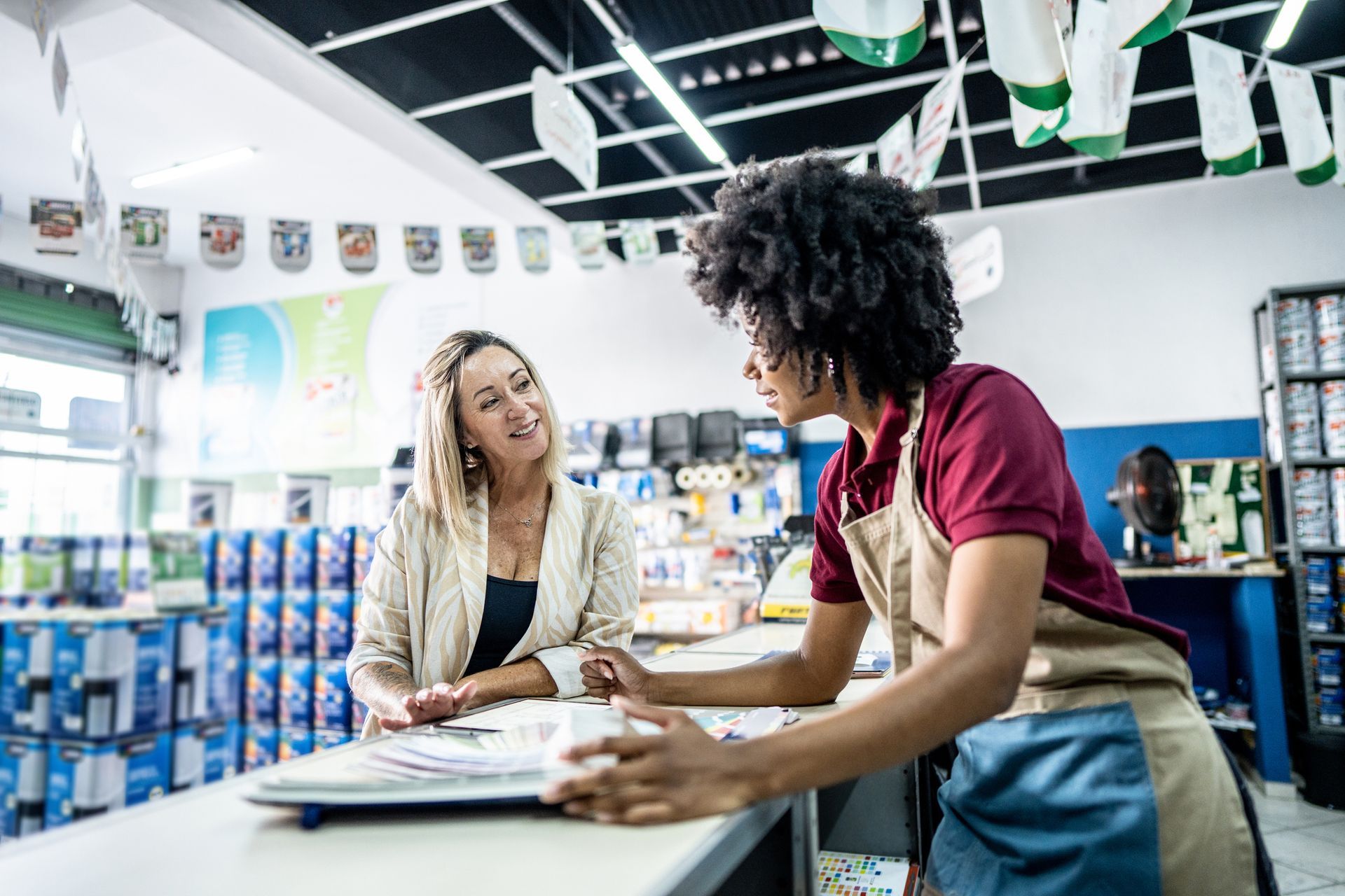 A saleswoman is attending a customer at a paint store.