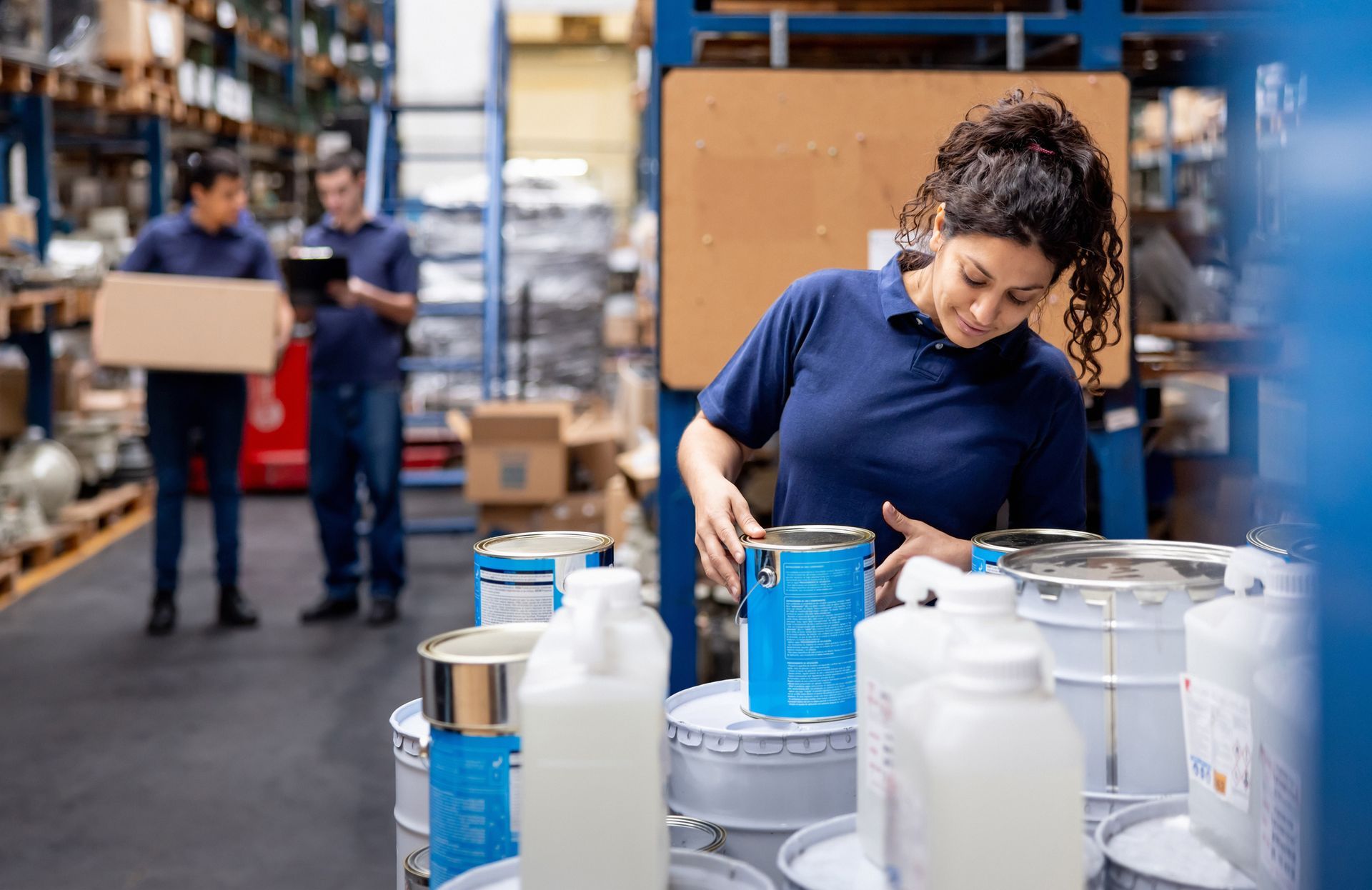 An employee is organizing cans of paint at a distribution warehouse.