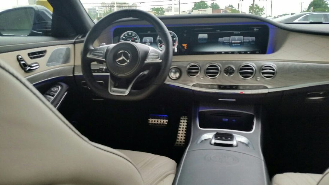 Interior of a Mercedes-Benz car, showing dashboard, steering wheel, and front seats in beige and black.