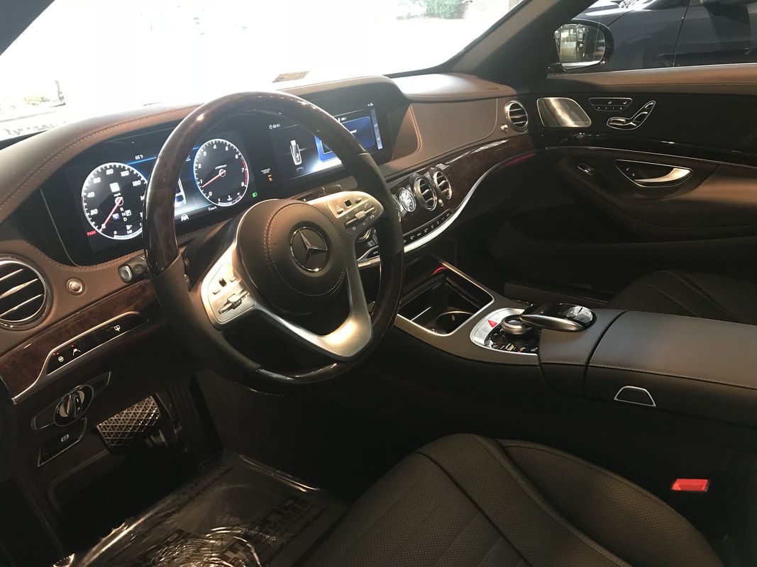 Interior view of a Mercedes-Benz car: brown and black dashboard, steering wheel, and seats.