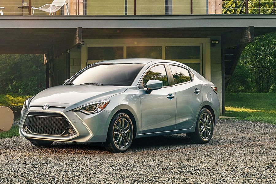 Silver Toyota Yaris sedan parked on gravel driveway in front of a modern home.
