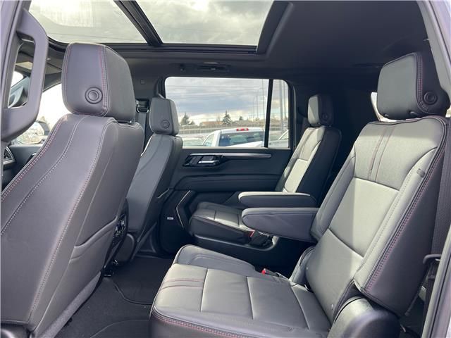 Interior of a black SUV with leather seats, a panoramic sunroof, and outdoor view.