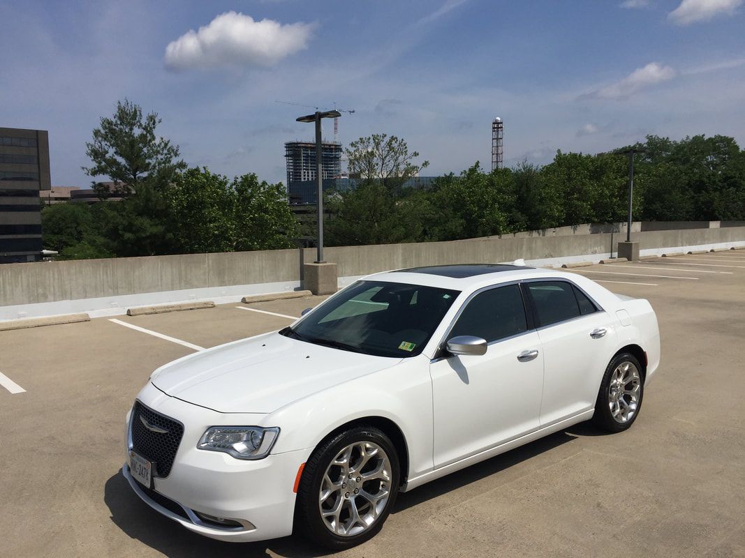 White Chrysler 300 sedan parked in a parking garage on a sunny day.