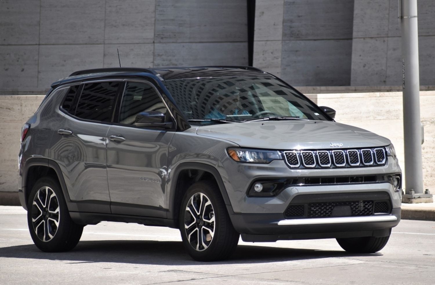 Gray Jeep Compass parked near a modern building. Black roof and accents.