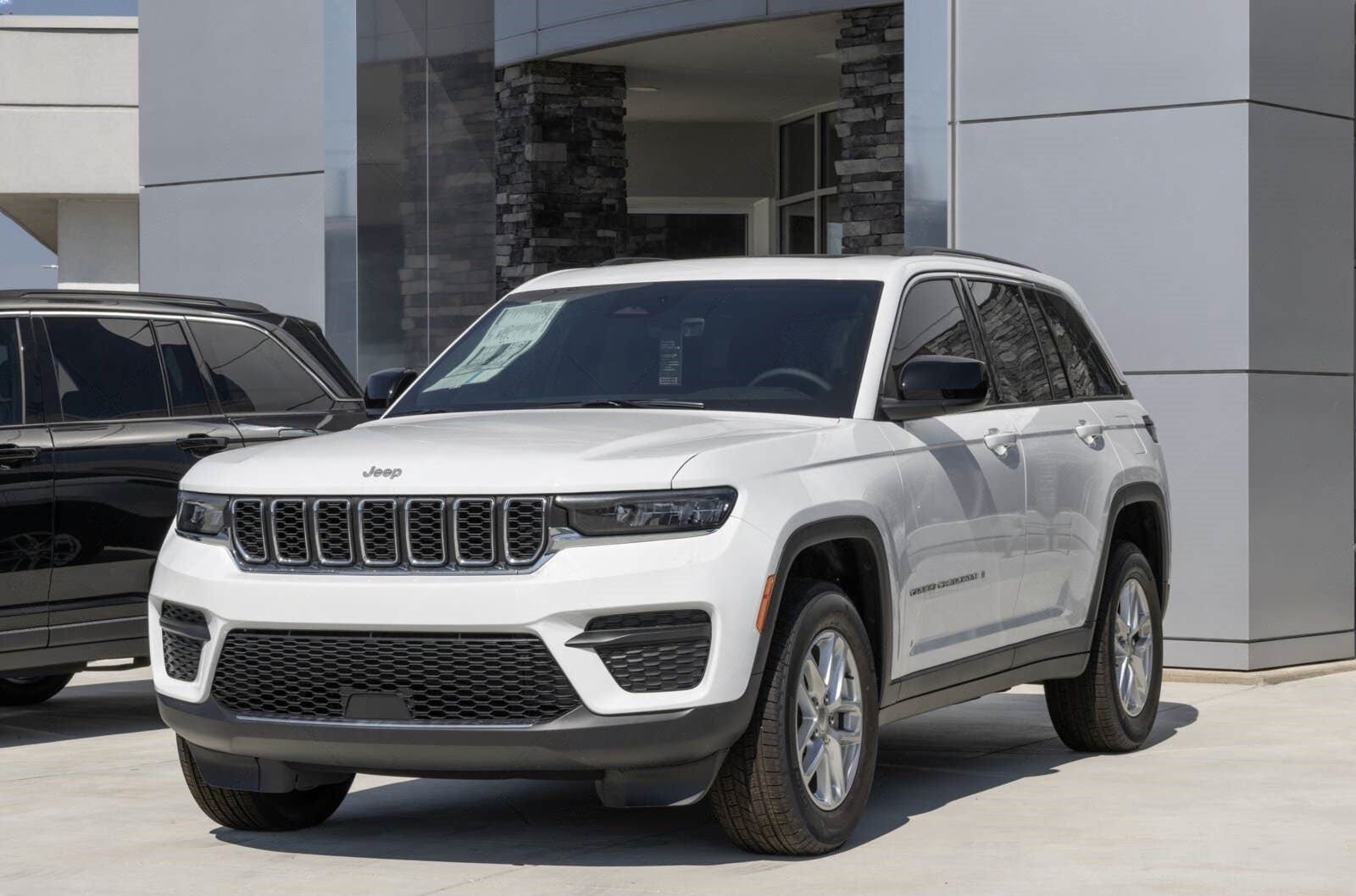White Jeep Grand Cherokee parked in front of a modern building with black accents.
