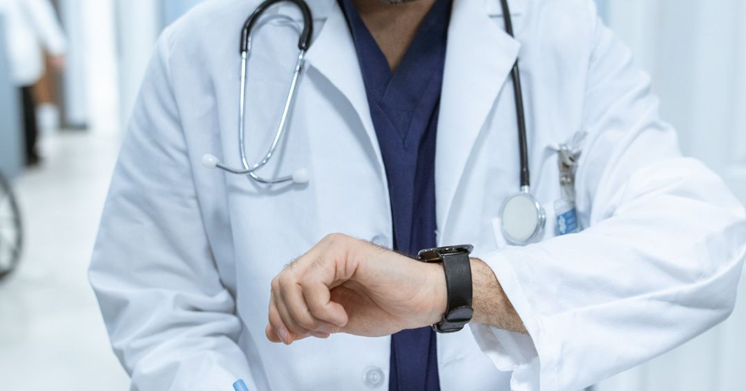 a doctor is looking at his watch while holding a clipboard .
