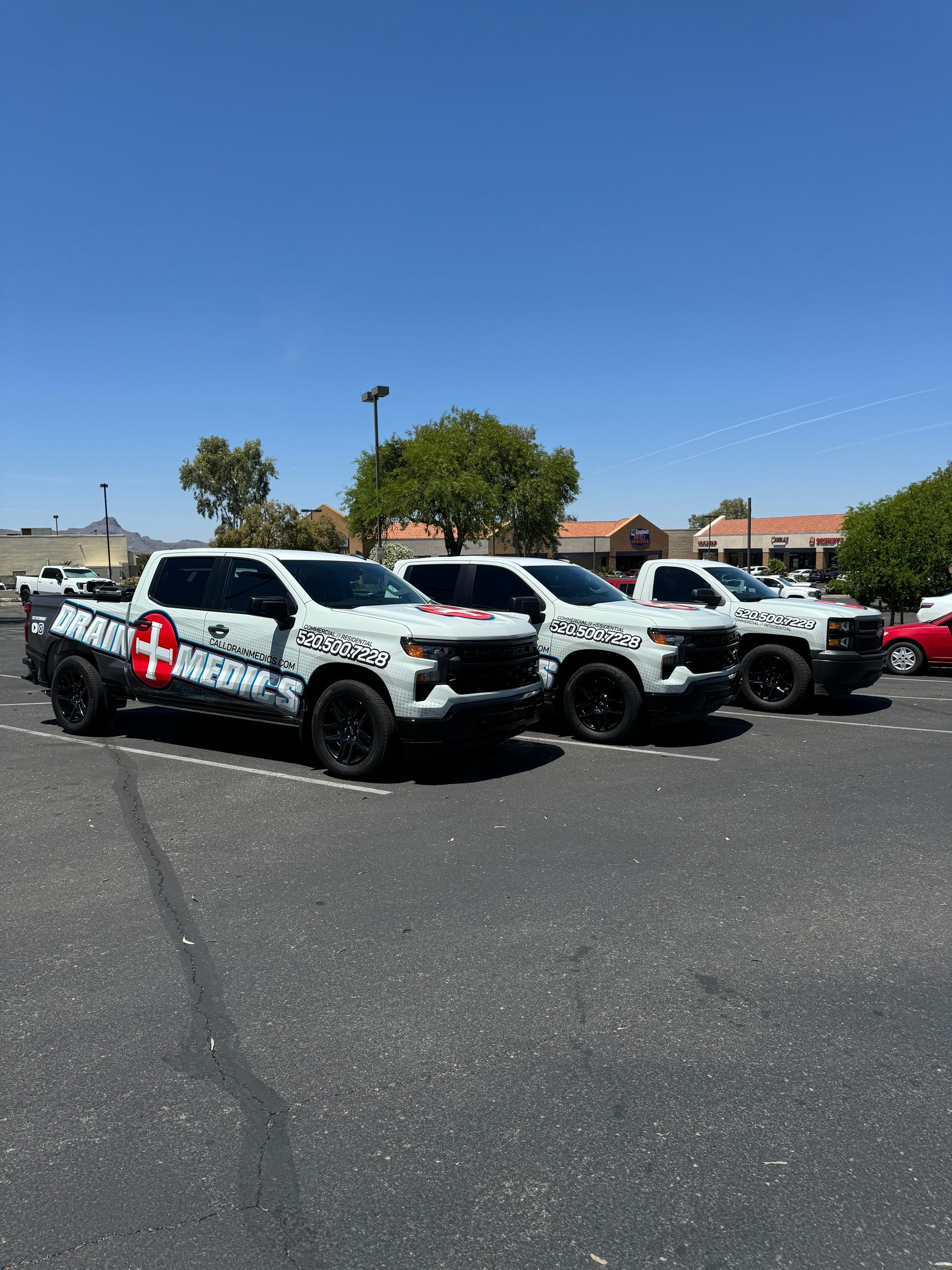 A row of white trucks are parked in a parking lot.