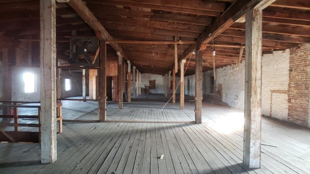 A large empty room with wooden floors and brick walls
