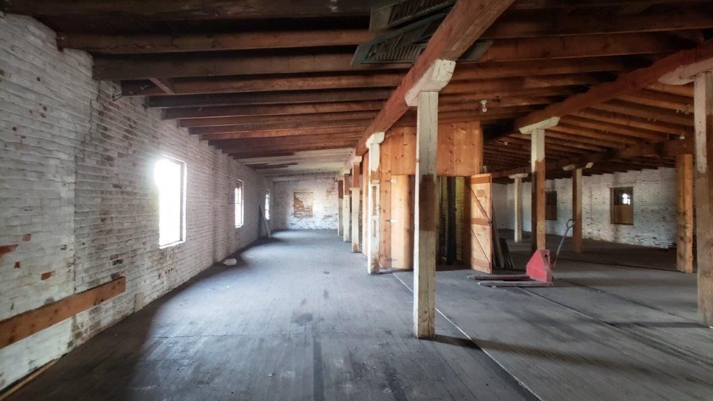 A large empty room with brick walls and wooden beams.