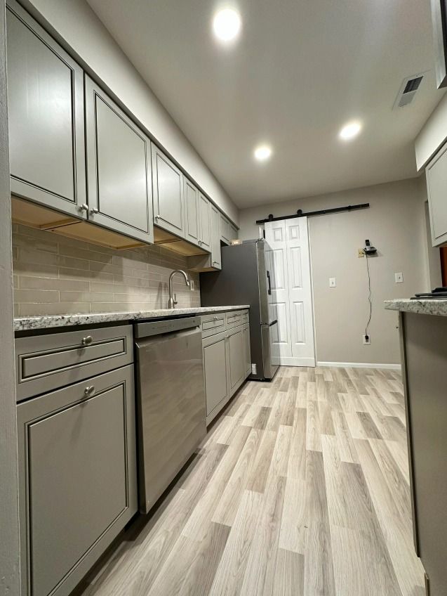 A kitchen with stainless steel appliances and a sliding barn door.