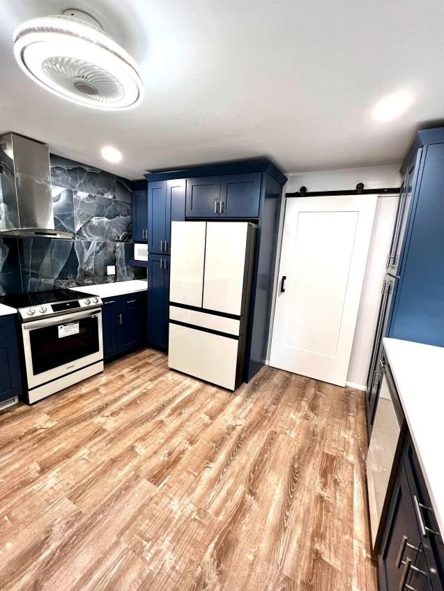 A kitchen with blue cabinets , stainless steel appliances , a refrigerator and a stove.
