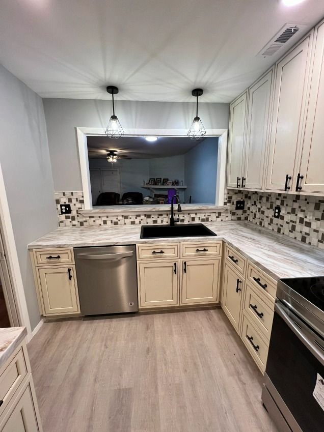 A kitchen with white cabinets , stainless steel appliances , a sink , and a window.