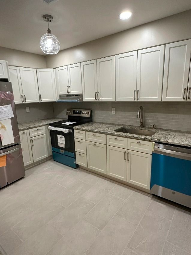 A kitchen with white cabinets , granite counter tops , stainless steel appliances and a stove.