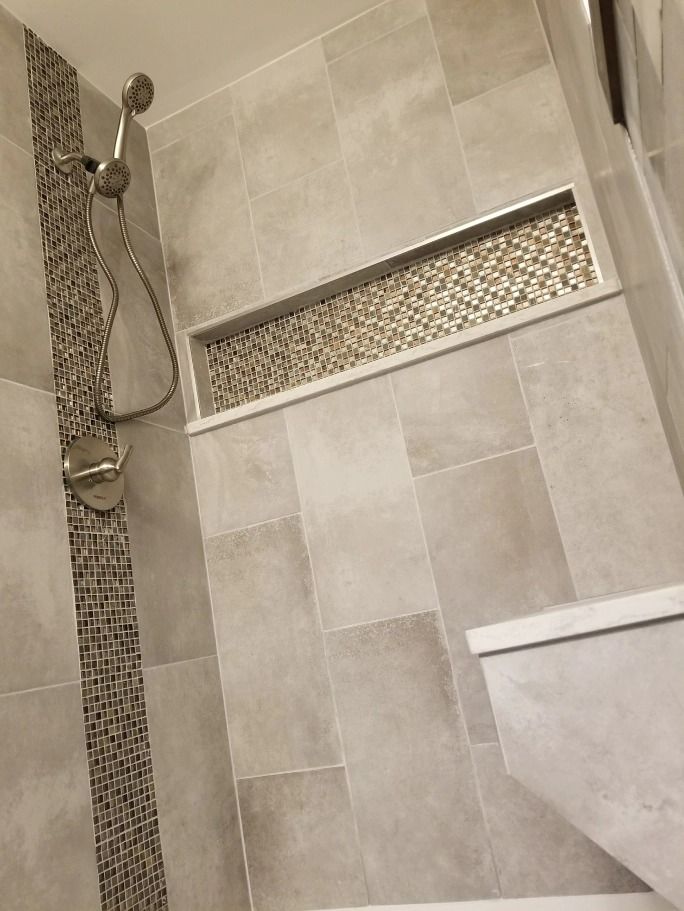A shower with a shower head and a shelf in the wall.