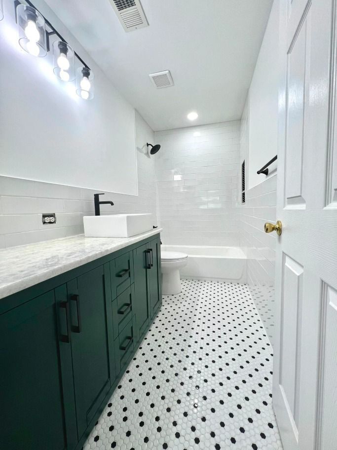 A bathroom with a sink , toilet , bathtub and polka dot floor.