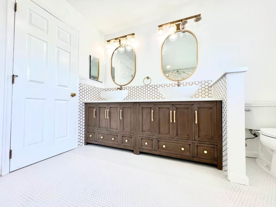 A bathroom with two sinks , two mirrors and a toilet.