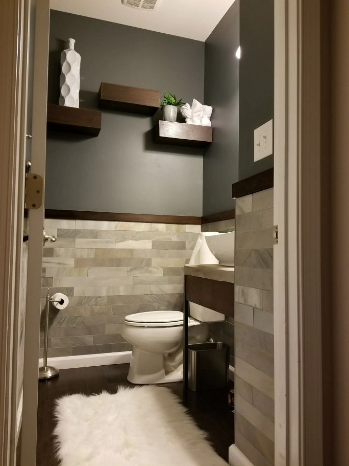 A bathroom with a toilet , sink , and shelves.