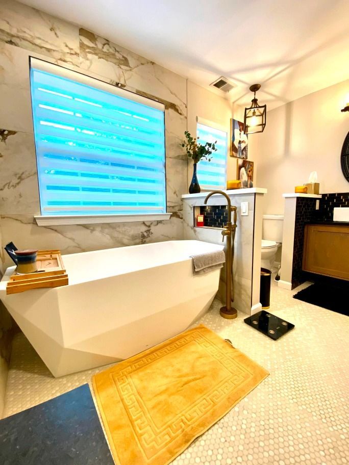 A bathroom with a tub , sink , toilet and window.