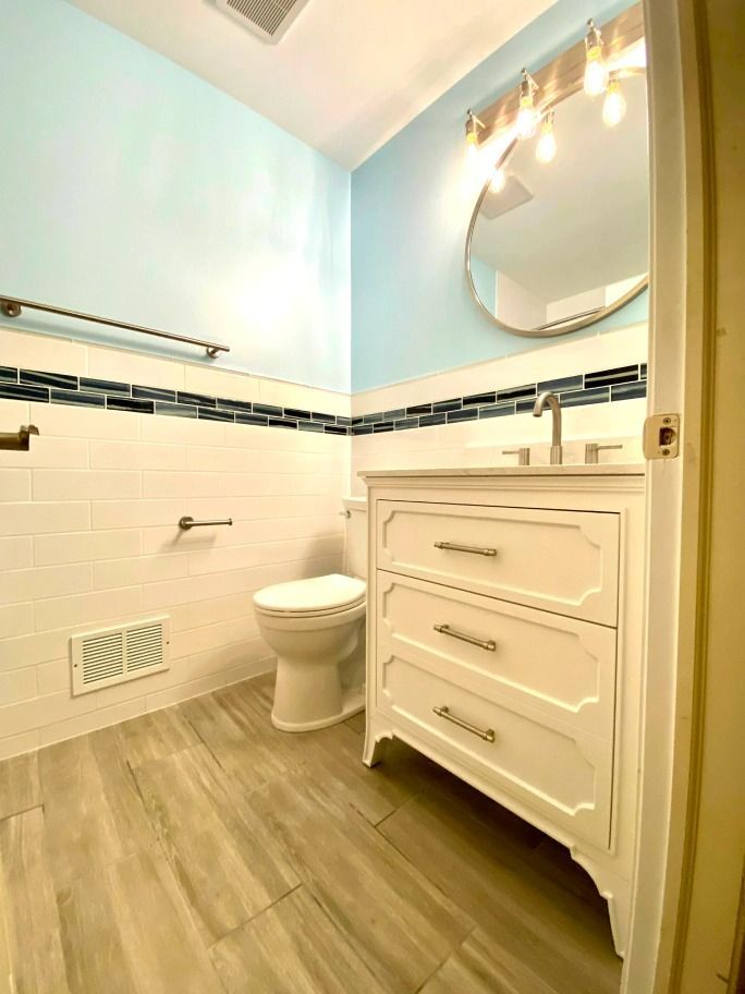 A bathroom with a toilet , sink and mirror.