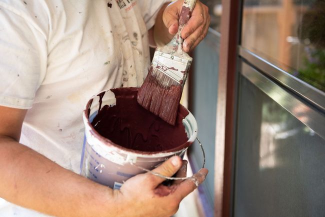 A person is holding a bucket of paint and a brush.