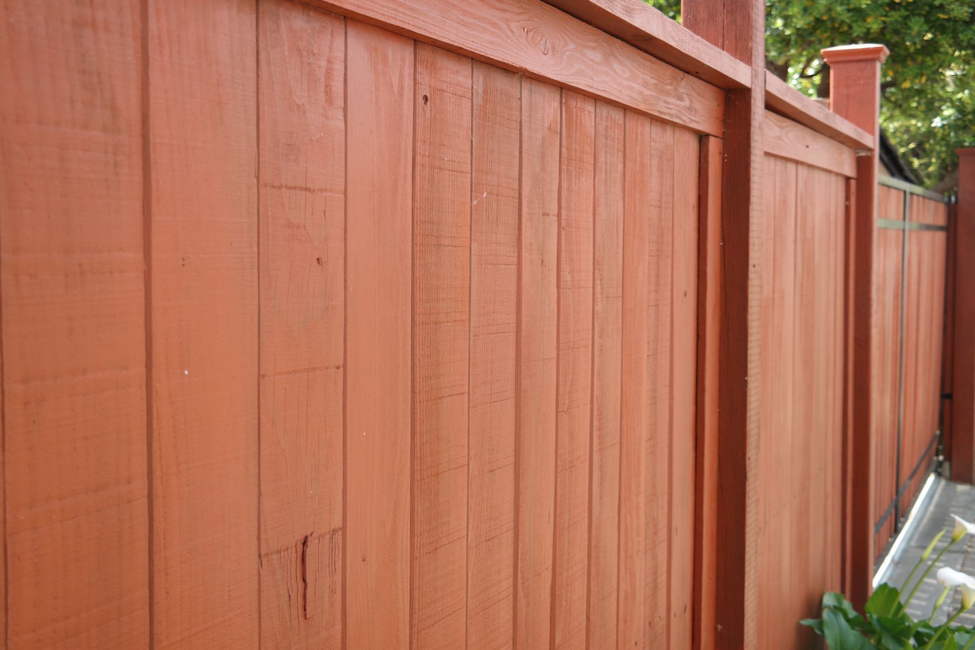 A close up of a red wooden fence with a chimney in the background.