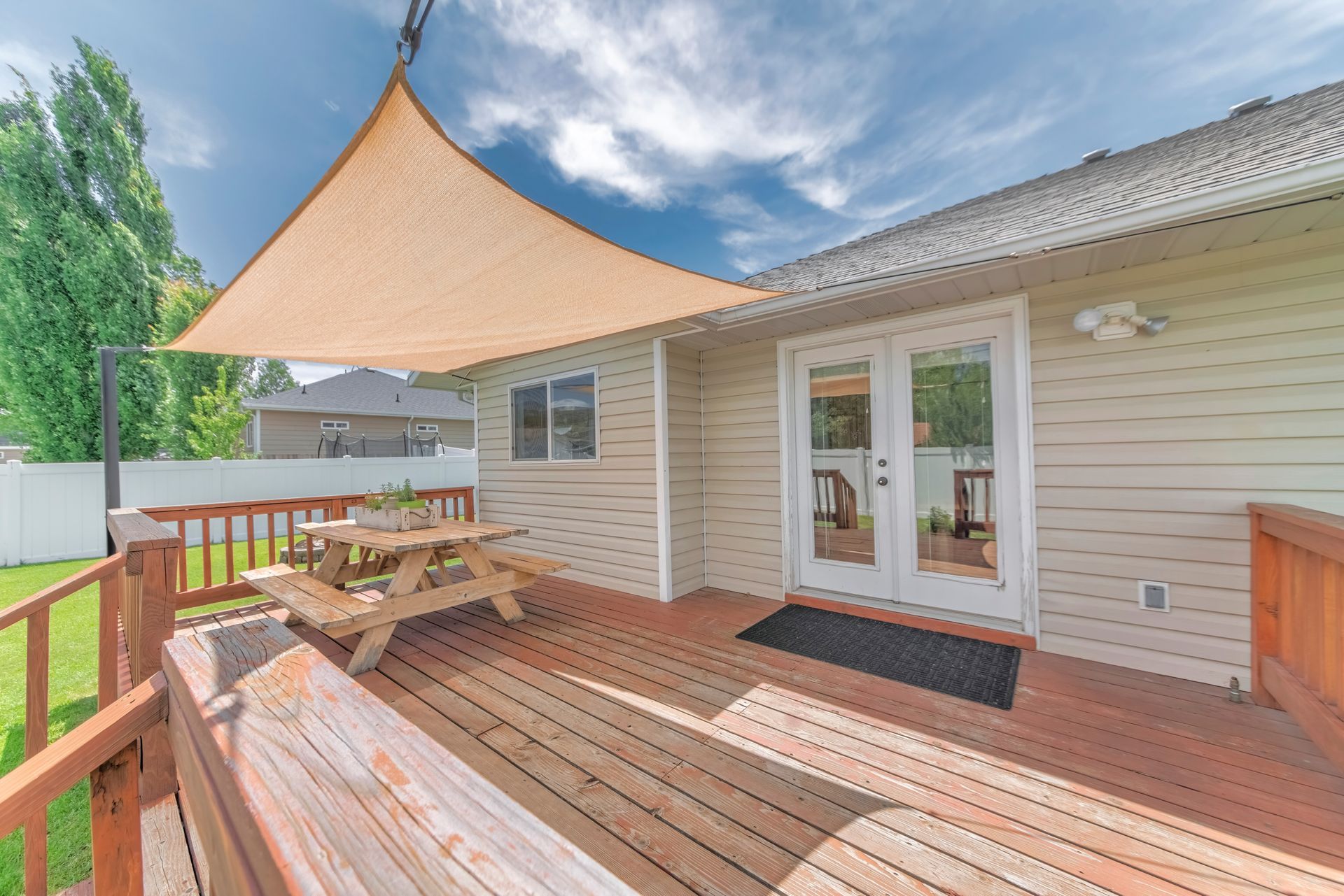 A wooden deck with a picnic table and a canopy over it.