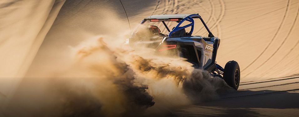 A person is driving a dune buggy on a dirt road.