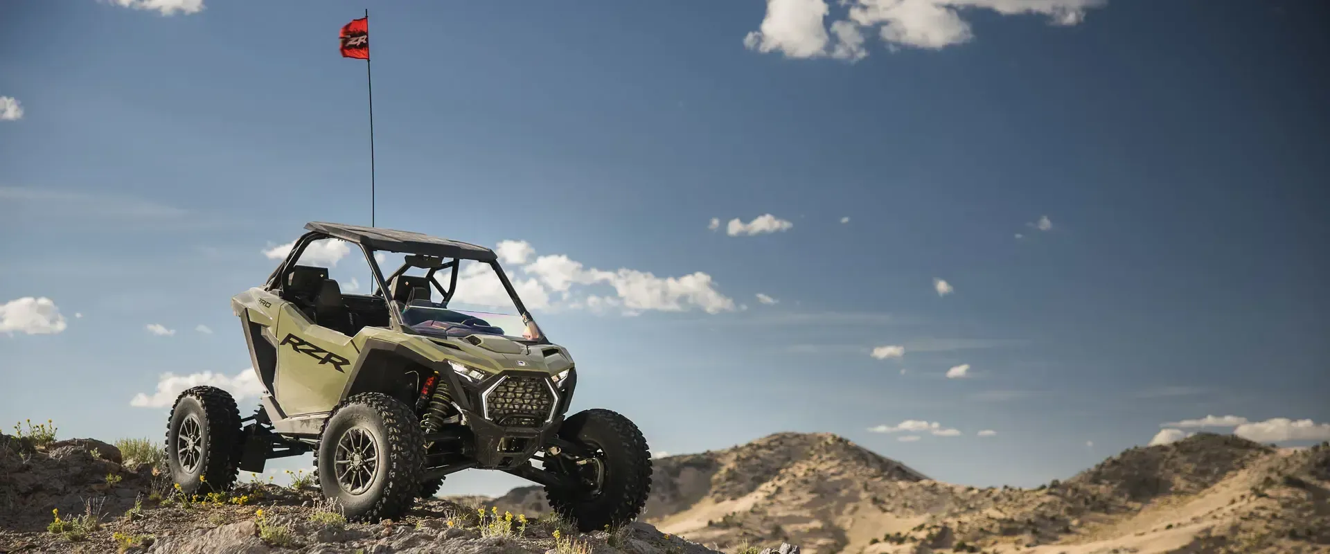 A green atv is parked on top of a hill in the desert.