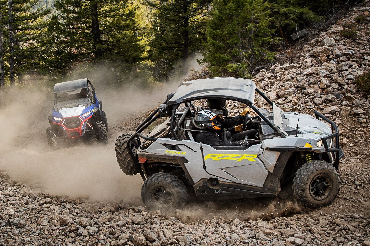 A couple of atvs are driving down a dirt road.