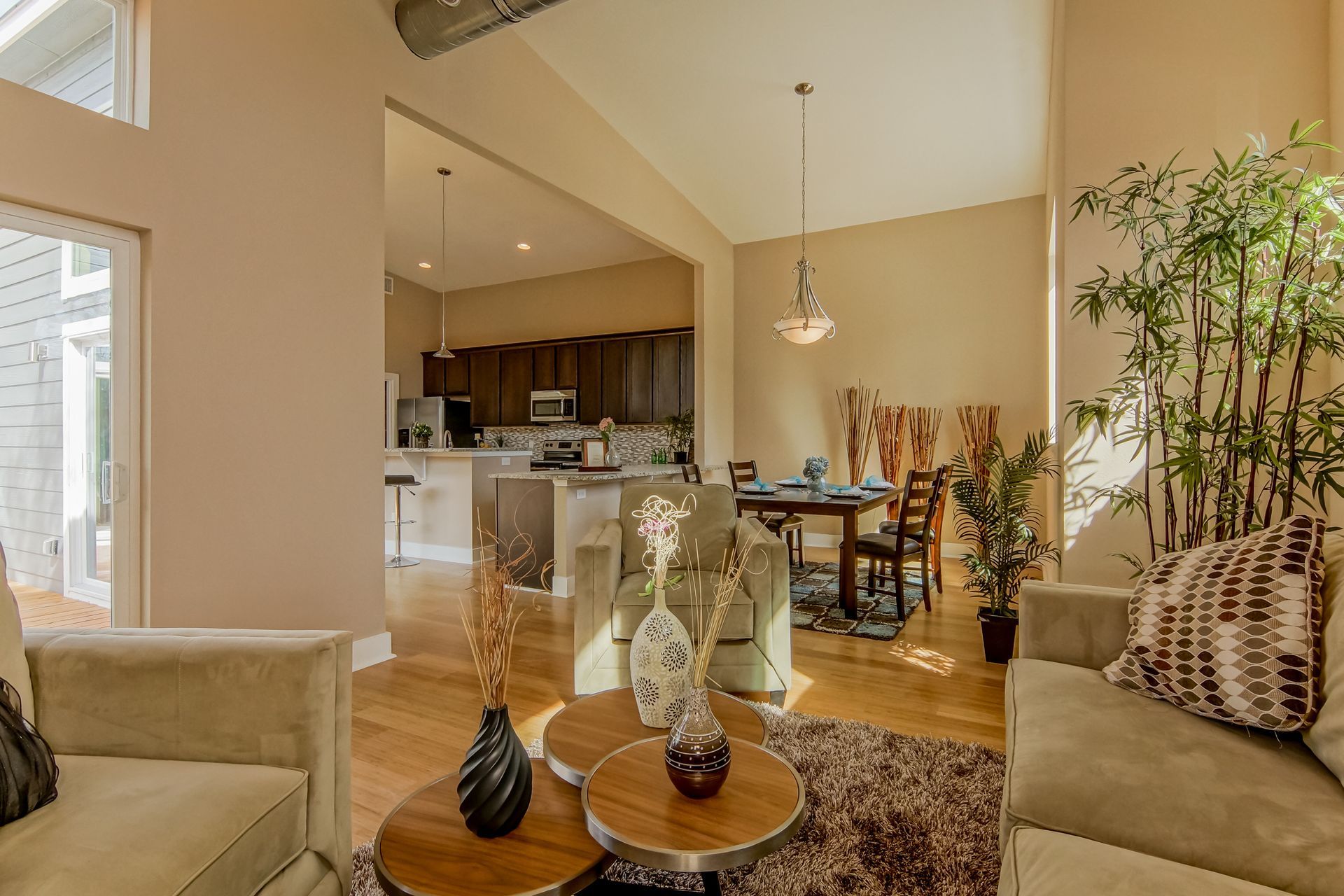 A modern living room with beige sofas, two small round coffee tables, and a dining area in the background.