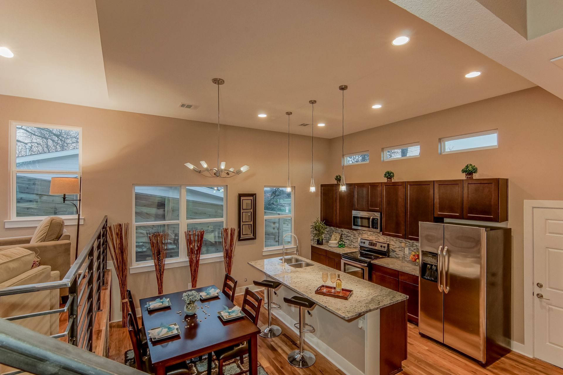 A high-angle view of a kitchen and dining area featuring dark wooden cabinets, granite countertops, and a dining table.