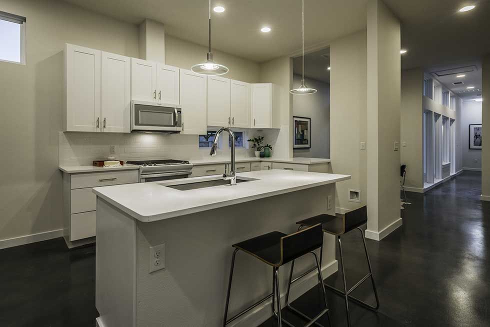 Modern kitchen featuring white cabinets, stainless steel appliances, a center island with bar stools, and dark floors.