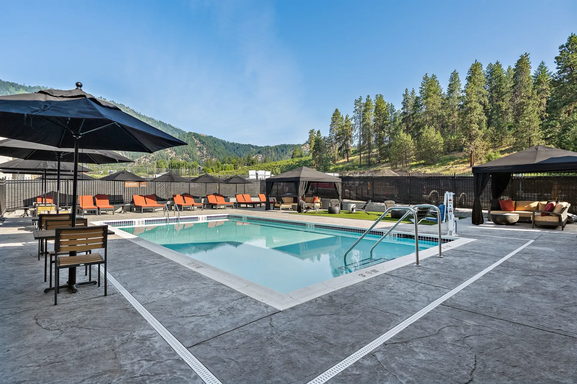 A large swimming pool surrounded by chairs and umbrellas