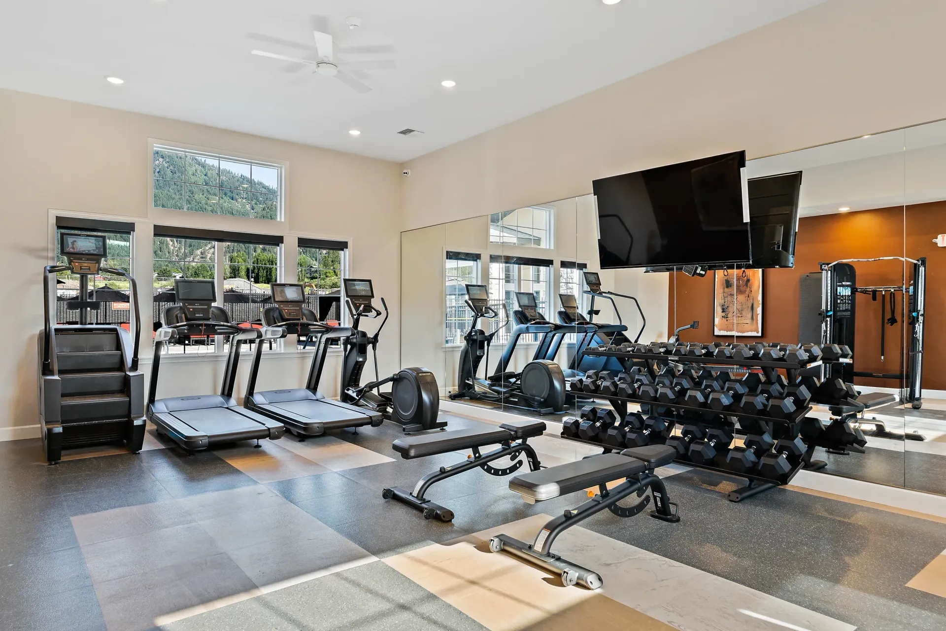A large gym with a lot of equipment and a large mirror.
