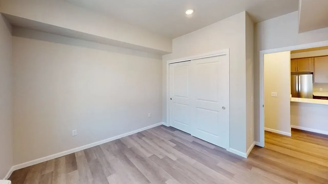 An empty bedroom with hardwood floors and a closet.