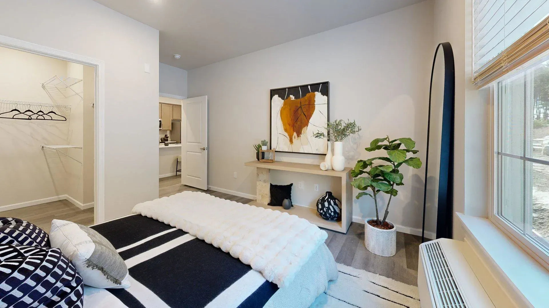 A bedroom with a large bed , a painting on the wall , and a window.