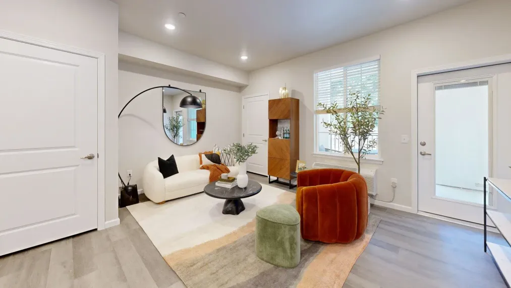 A living room with a couch , chair , table and mirror.