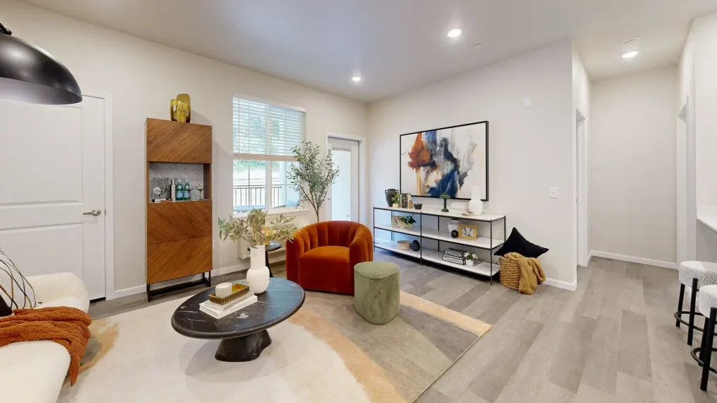 A living room with a couch , chair , coffee table and painting on the wall.