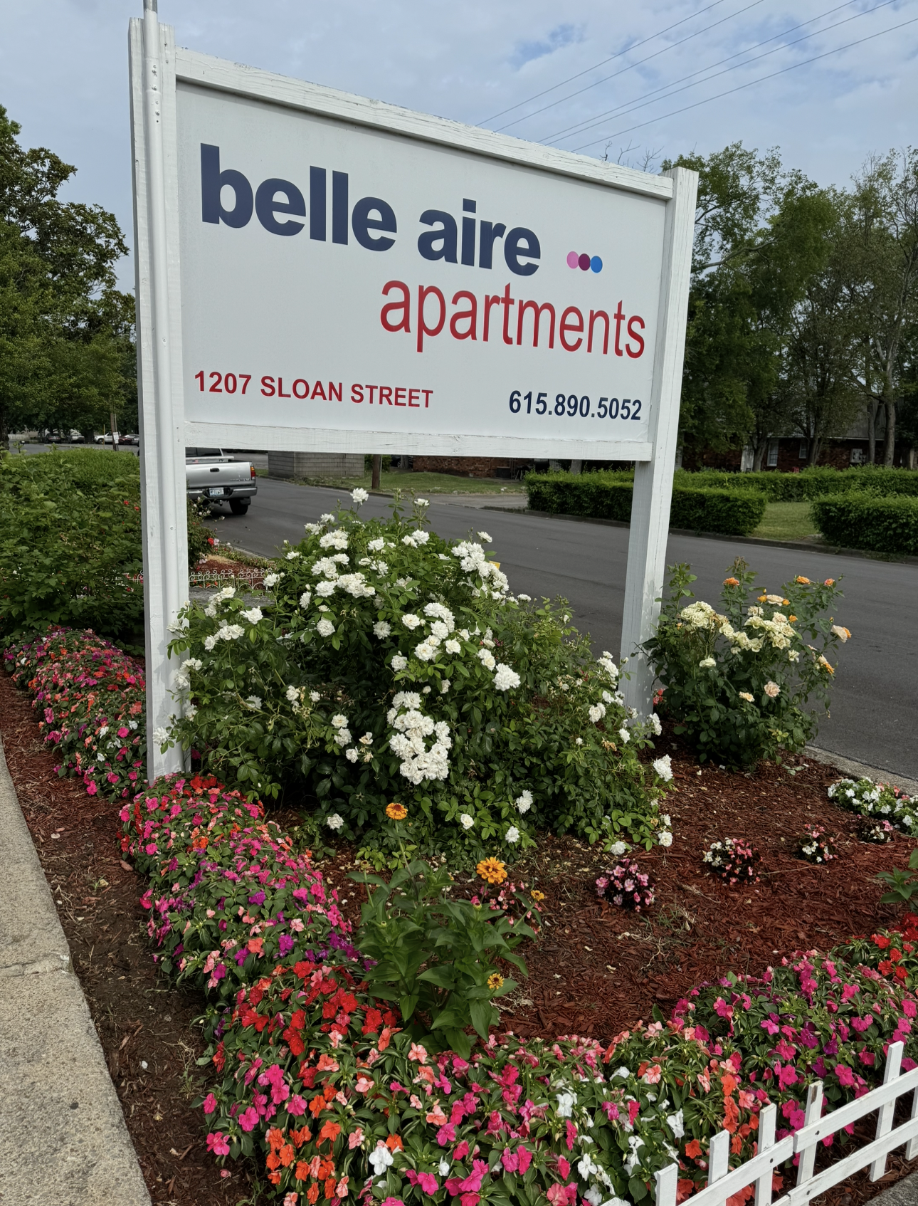 White kitchen with refrigerator, cabinets, stove, and sink. Gray countertop and flooring.