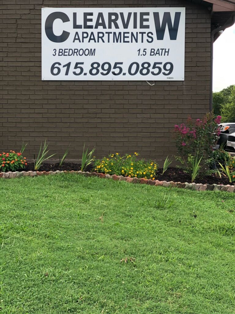 Empty room with light wood-look flooring, tan walls, and an open doorway letting in sunlight.
