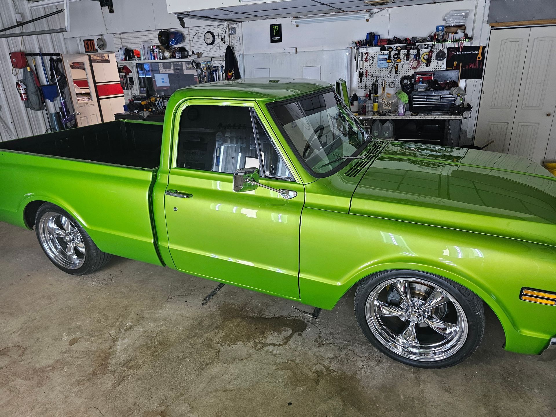 Bright green classic pickup truck parked in a garage with chrome wheels.