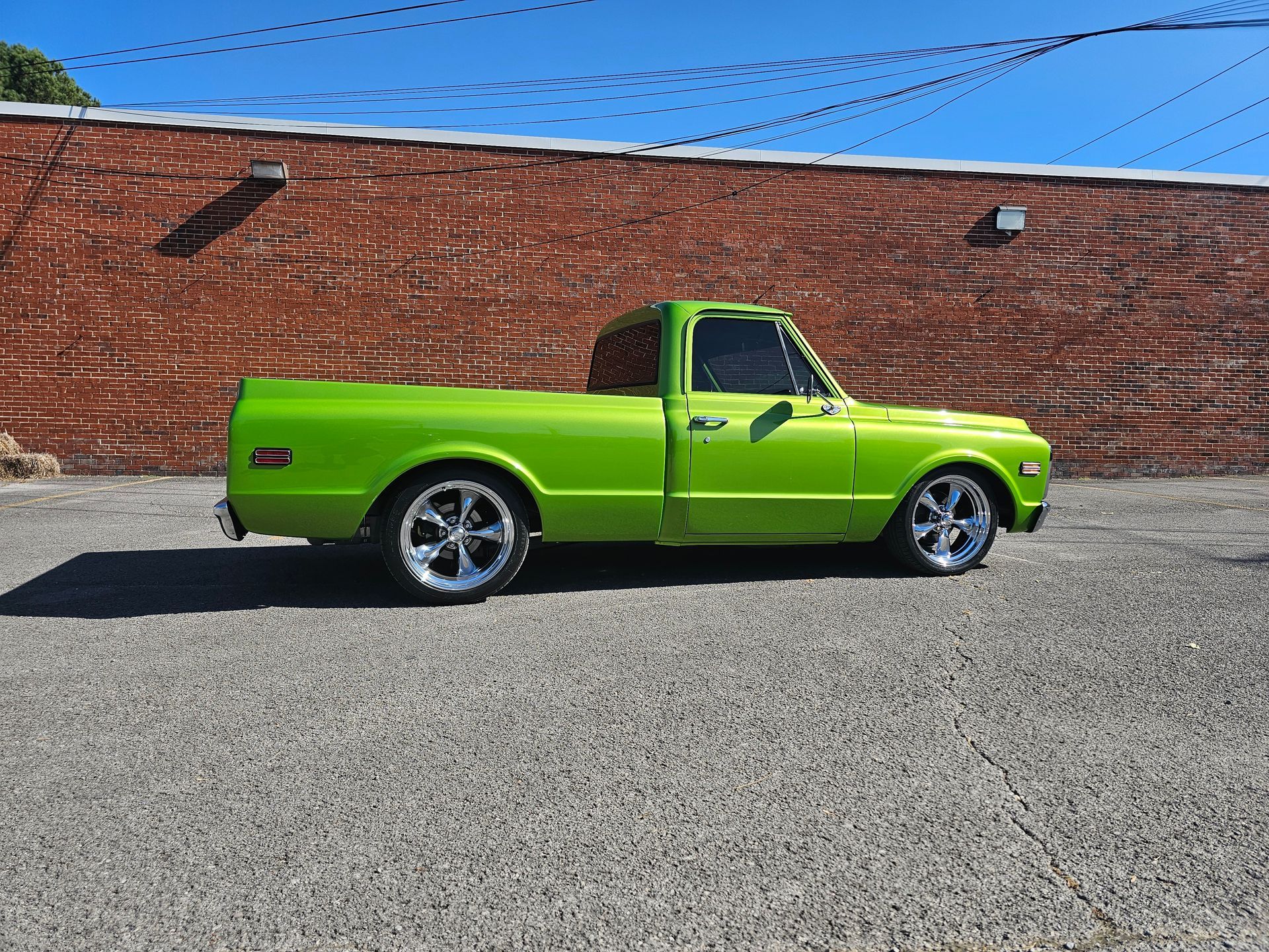 Bright green classic pickup truck parked in front of a brick building.