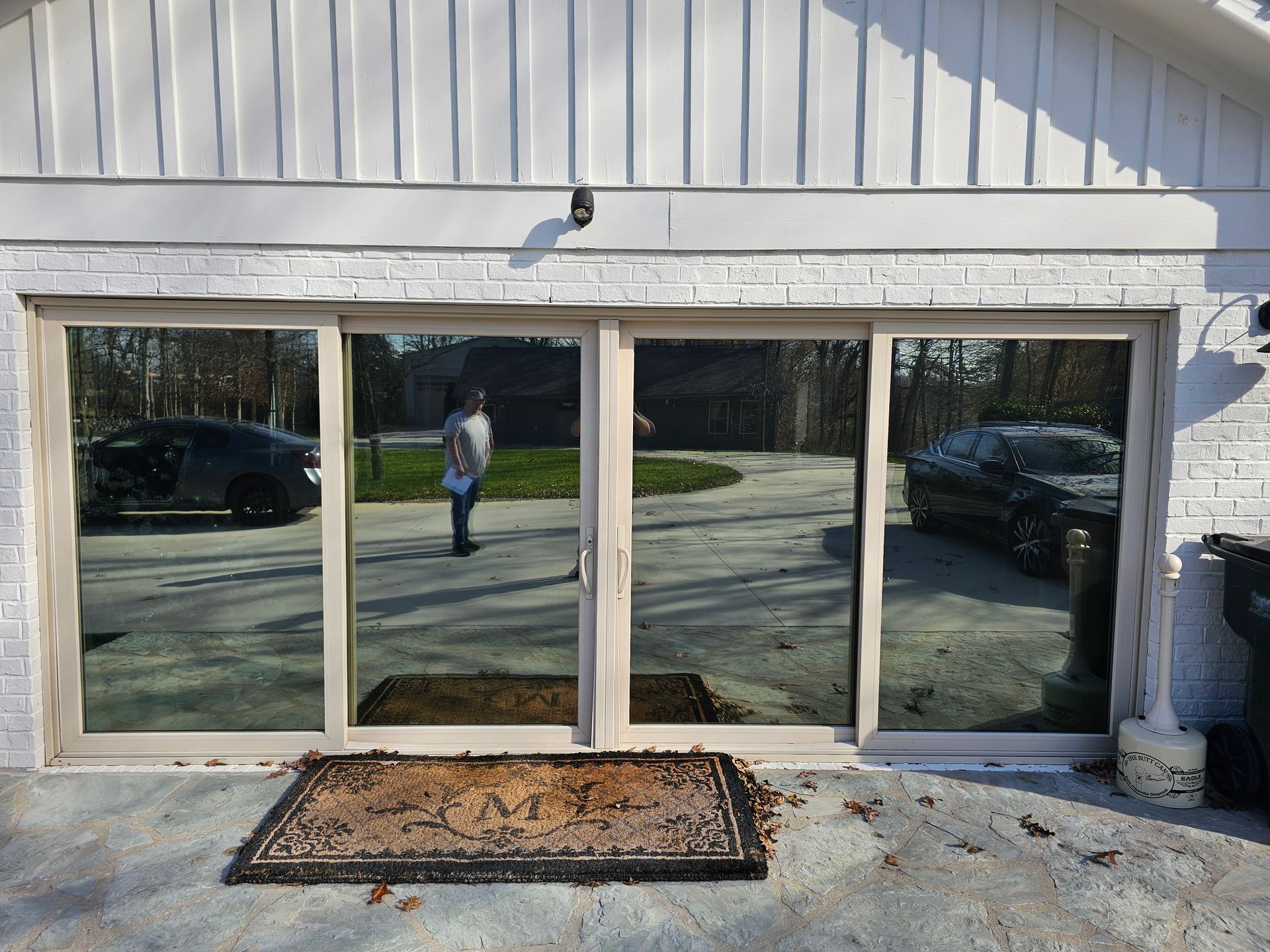 A man is standing in front of a house with a sliding glass door.