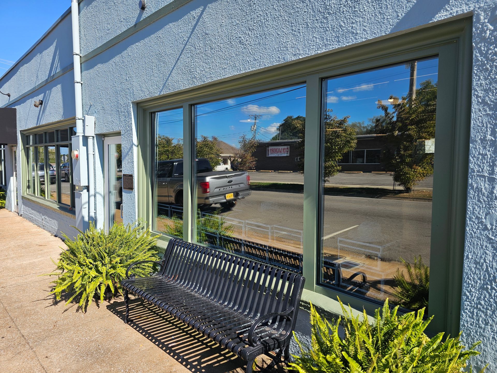 A bench is sitting in front of a building with a lot of windows.