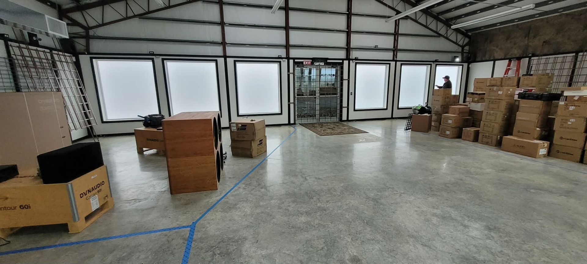 Interior of a warehouse with boxes, tables, and windows.