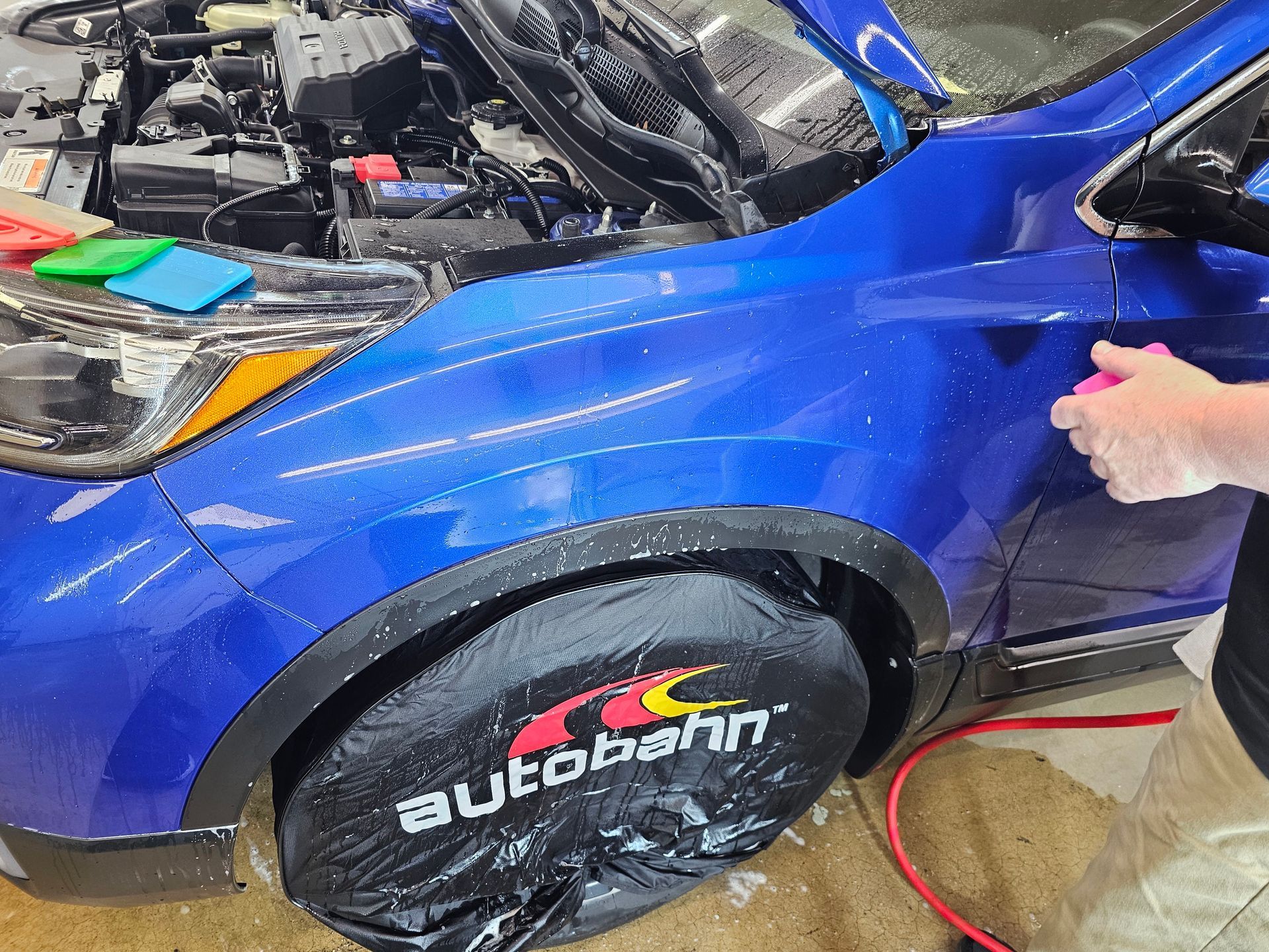 A group of people are working on a car in a garage.