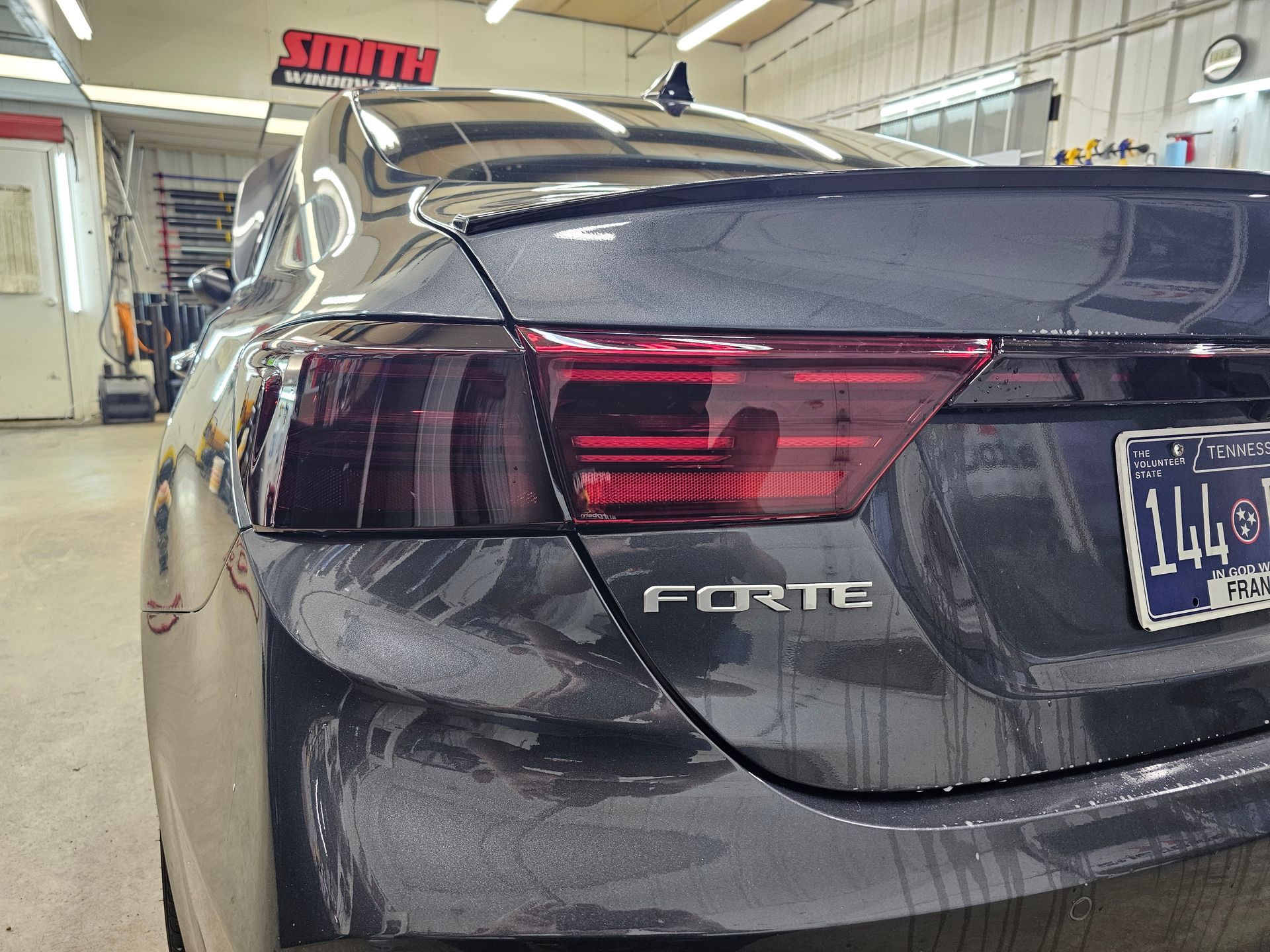 A black car with a license plate that says 1441 is parked in a garage.