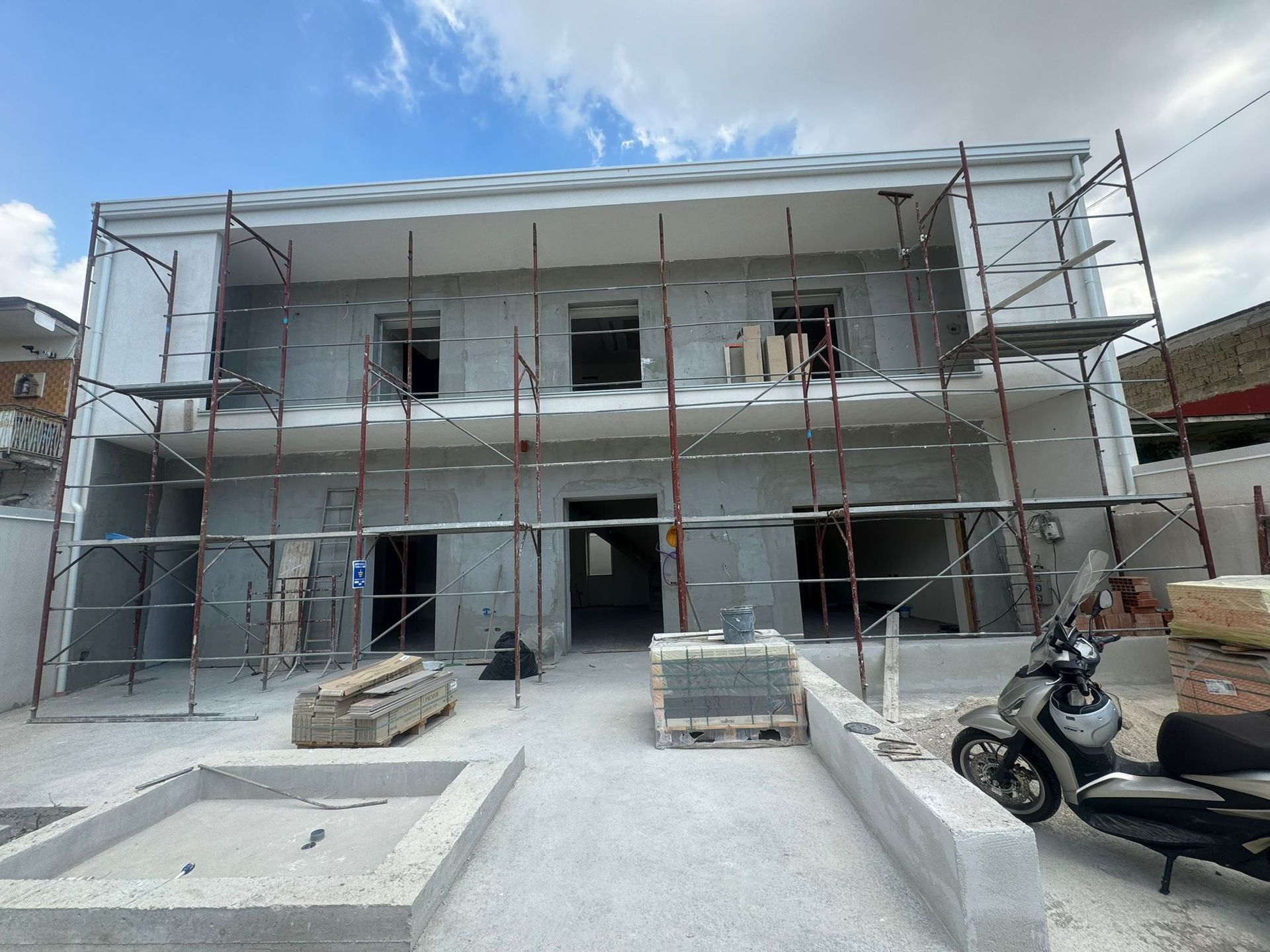 Un edificio in costruzione con impalcature e una motocicletta parcheggiata davanti.